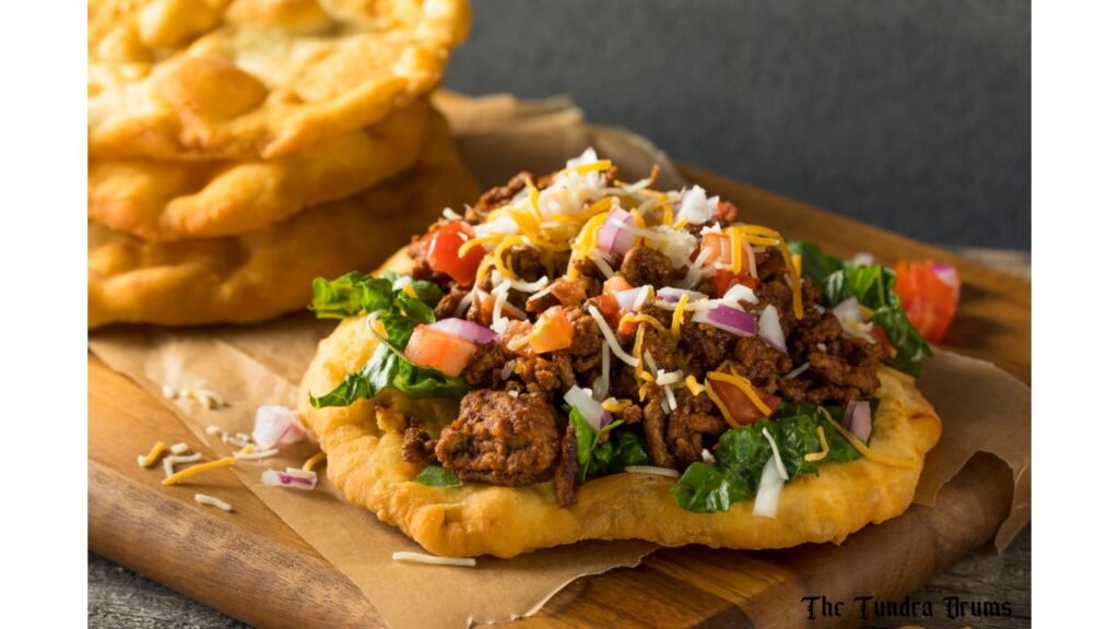 Fry bread with vegetables and meat on the top placed on a nice wood platter 