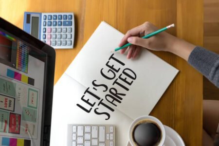 a girl is holding a pen and writing, while using laptop