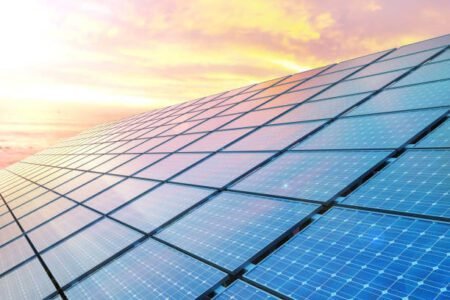 An aerial view of a vast solar panel field at sunset.