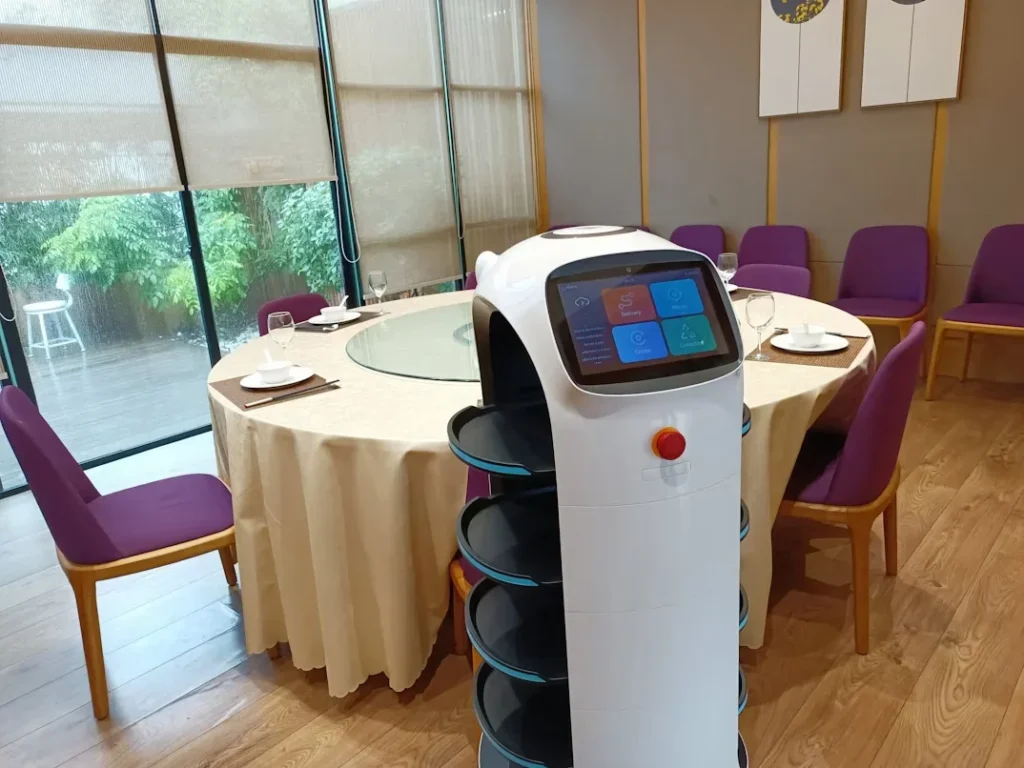 black and white robot stanidng next to dining table and chairs 1