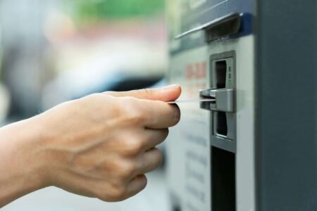 A person is putting an ATM card in the ATM machine.