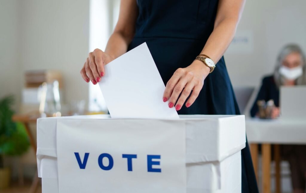 A woman is putting her voting paper in the ballot box.