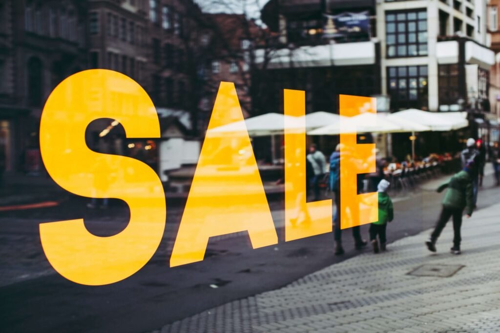 A yellow sale sign on a glass wall.