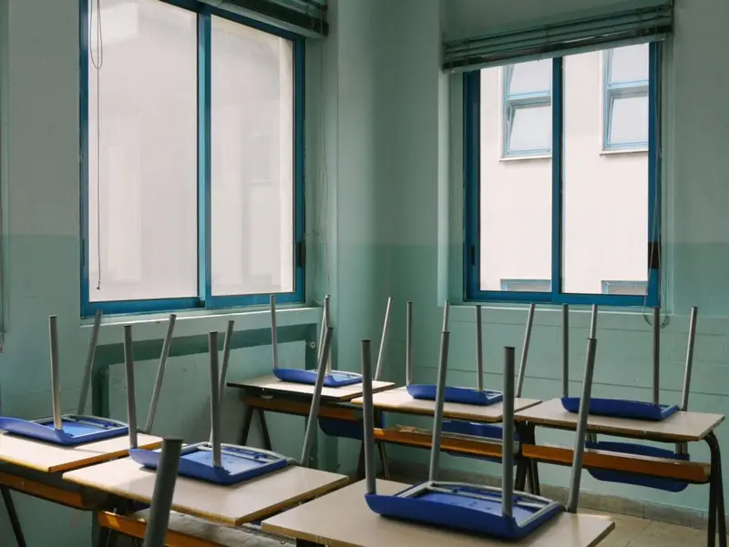 A view of a classroom with the chairs are on top of the desks.