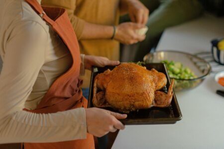 A woman is holding a tray with a turkey on it.