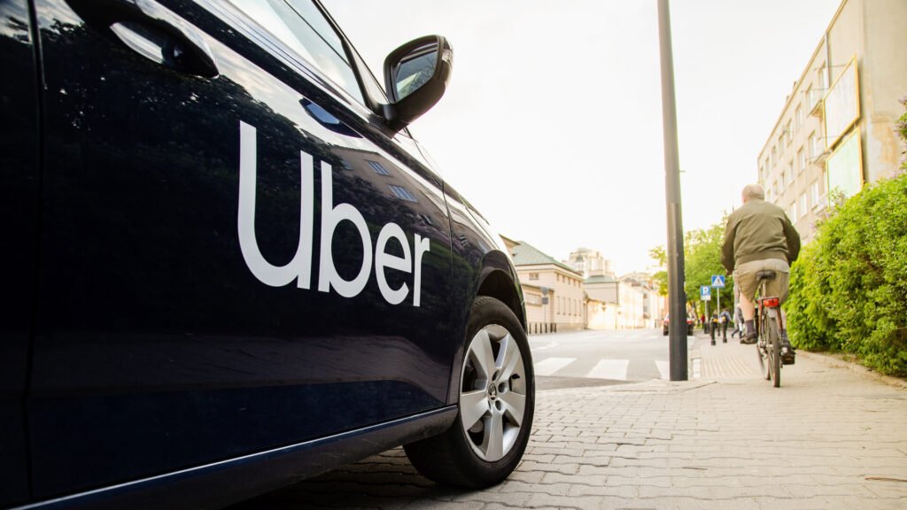 A black car with Uber written on its side parked on the side of the road.