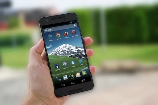 Cybersecurity Tips For iOS And Android Mobile Devices a person holding phone in his hands