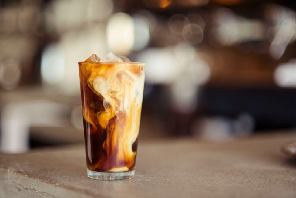 A glass cup of coffee on a table top.