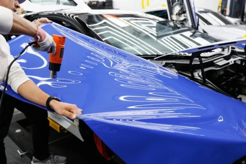 The Art and Science of Vinyl Car Wrapping: Tips, Techniques, and Trends man holding a power tool and blue sheet