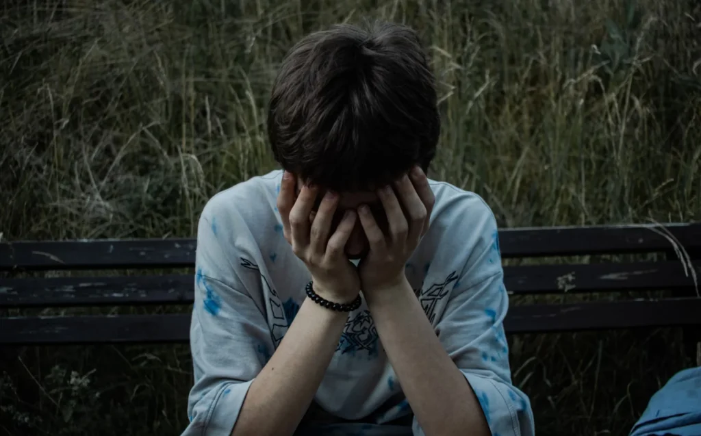 Wrongful Death Settlements: All the Losses and Damages that are Included a boy sitting on bench with hands on his face