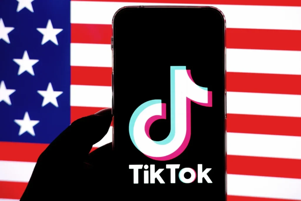 TikTok logo displayed on a phone in front of the US flag.