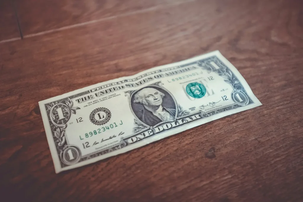 A US 1 dollar bill laying on top of a table.