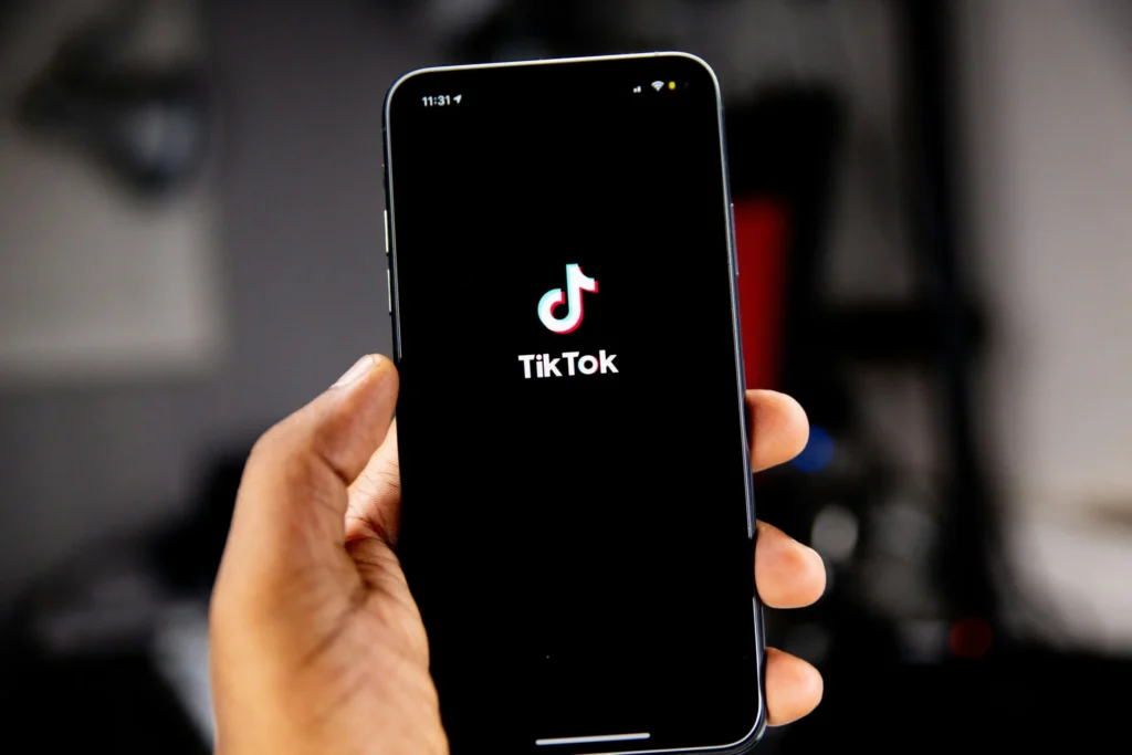 A person is holding a phone with TikTok´s logo on it.