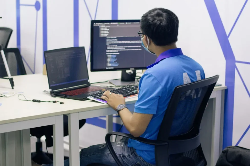 a man in blue shirt working sitting in front of computer