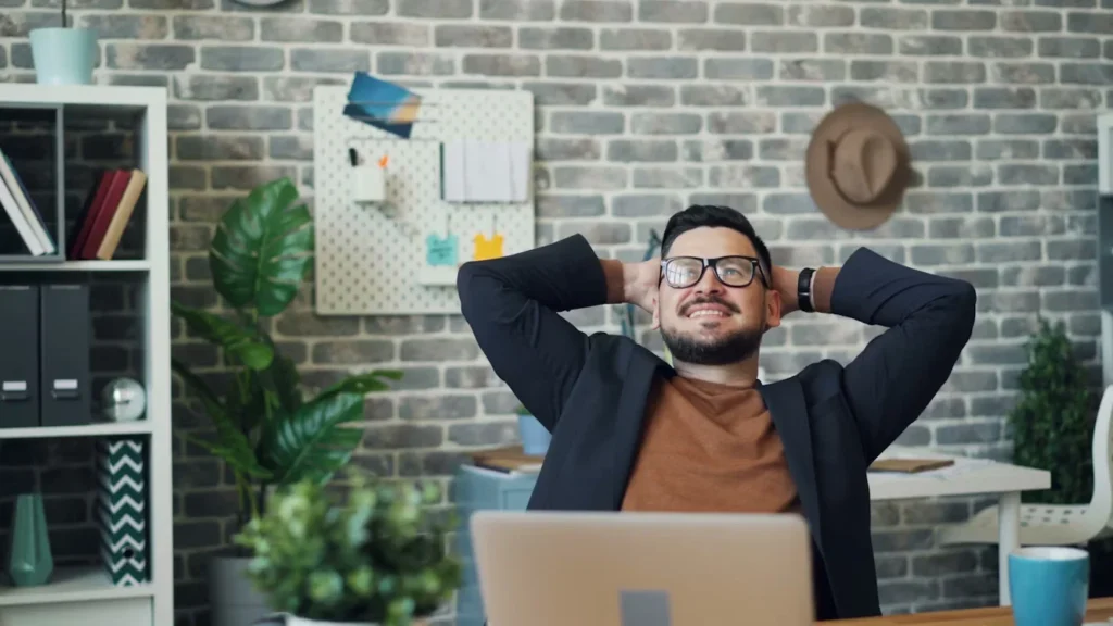 10 Employee Recognition Ideas That Drive Culture a man sitting on desk his hands behind his head.
