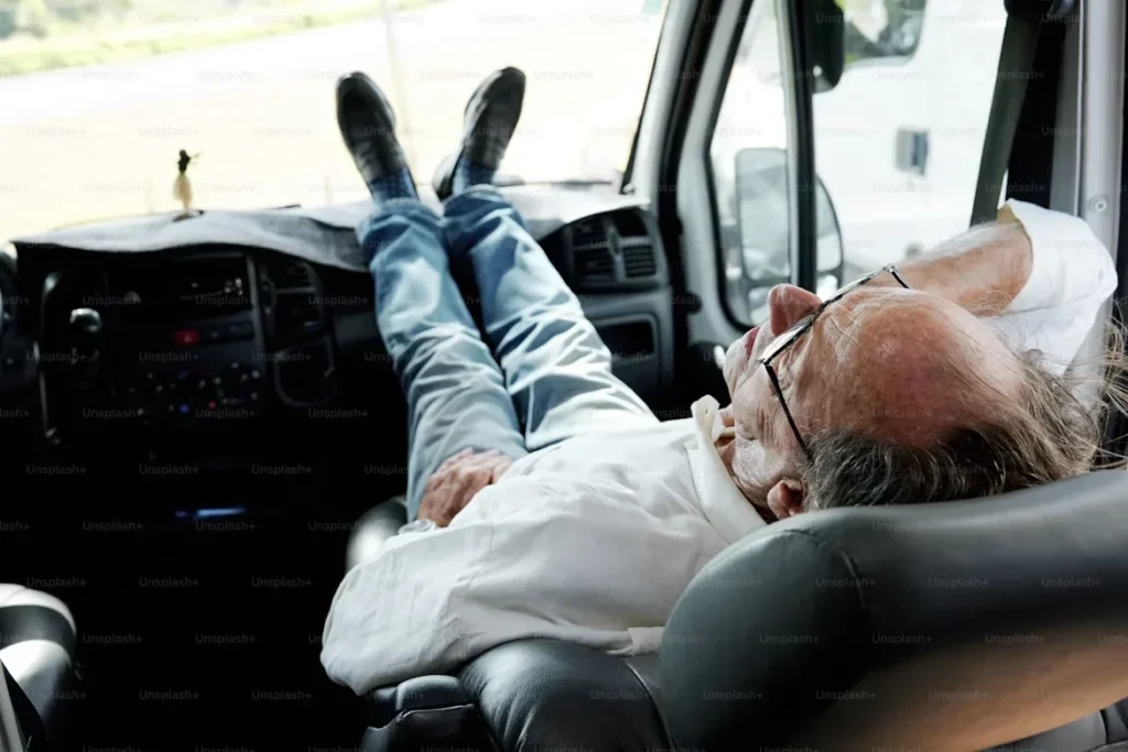 The Impact of Fatigue on Truck Drivers and How to Prevent It a man sleeping in car.