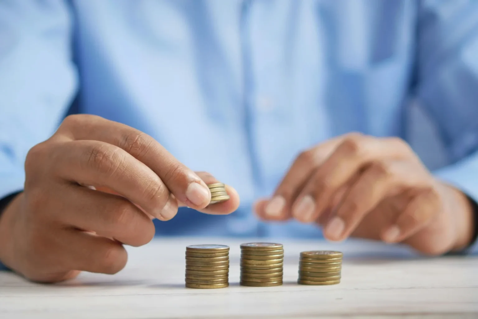 A person stacking coins on a table.