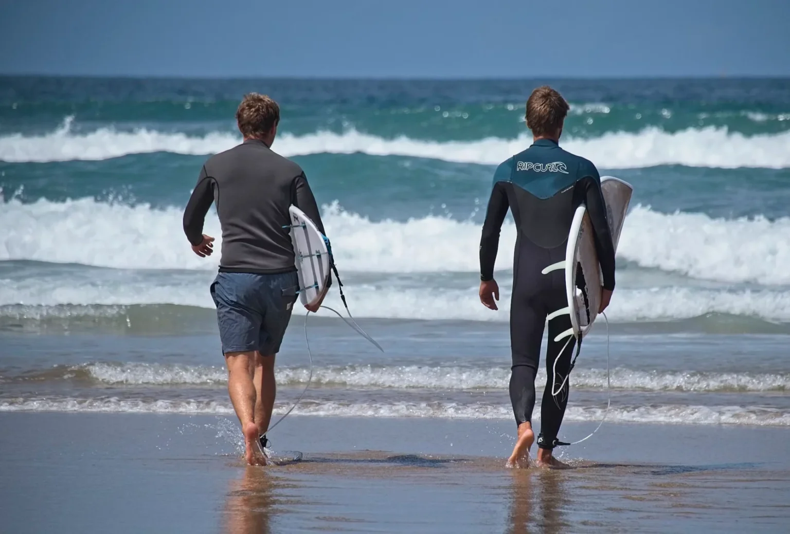 man wearing wetsuit holding surf board