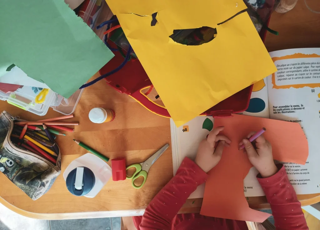 A child drawing on a colored sheet.