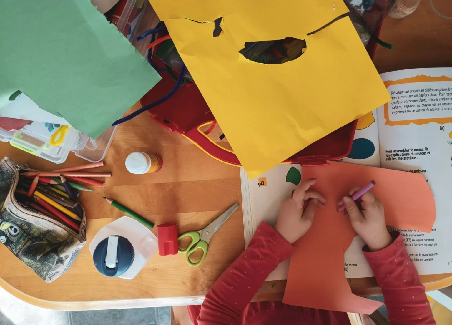 A child drawing on a colored sheet.