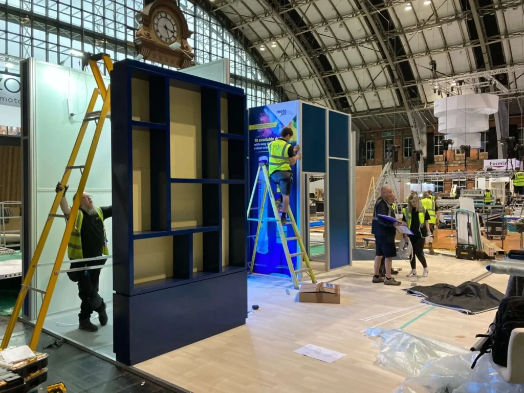 What Exactly Is an Exhibition Stand and Why Does My Brand Need One? a man is standing on a leader