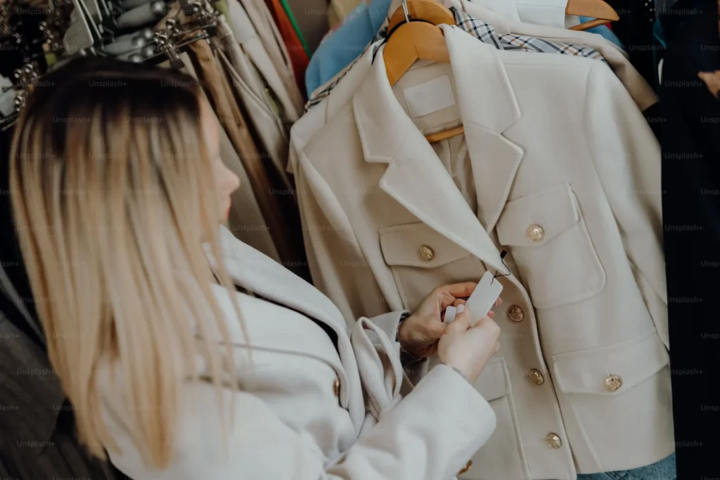 Beige Denim Clothing for a Neutral Look woman looking at a price tag of jacket