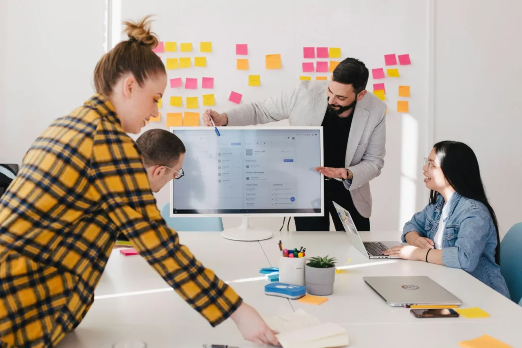 7 Benefits Business Coach Sessions Bring to New Startups man showing laptop screen to other colleges