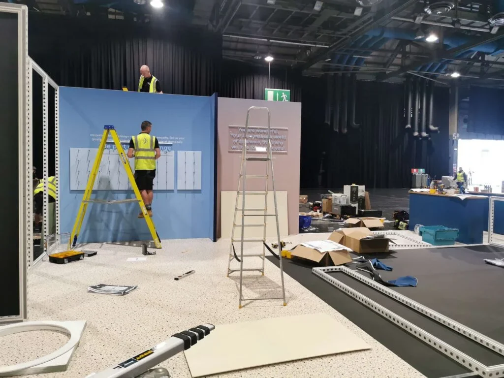 What Exactly Is an Exhibition Stand and Why Does My Brand Need One? Man is standing on a leader
