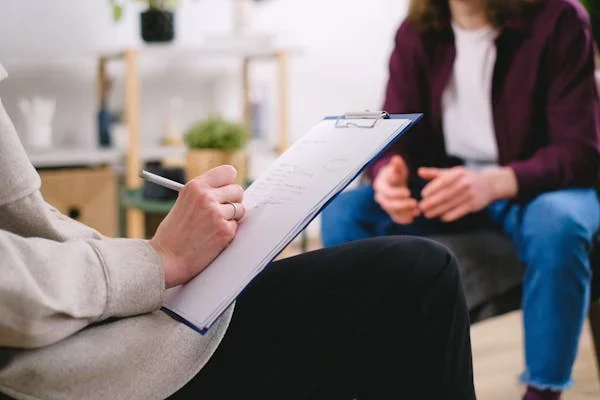 In-Home Mental Health Care vs Outpatient Clinics: Pros and Cons Therapist writing on paper