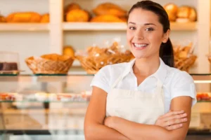 a woman wearing apron standing in bakery shop