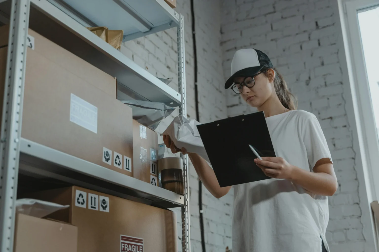 woman in white shirt holding a package and a clip board in ger hands