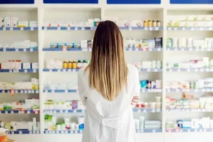 woman standing in pharmacy looking at medicines on shelves