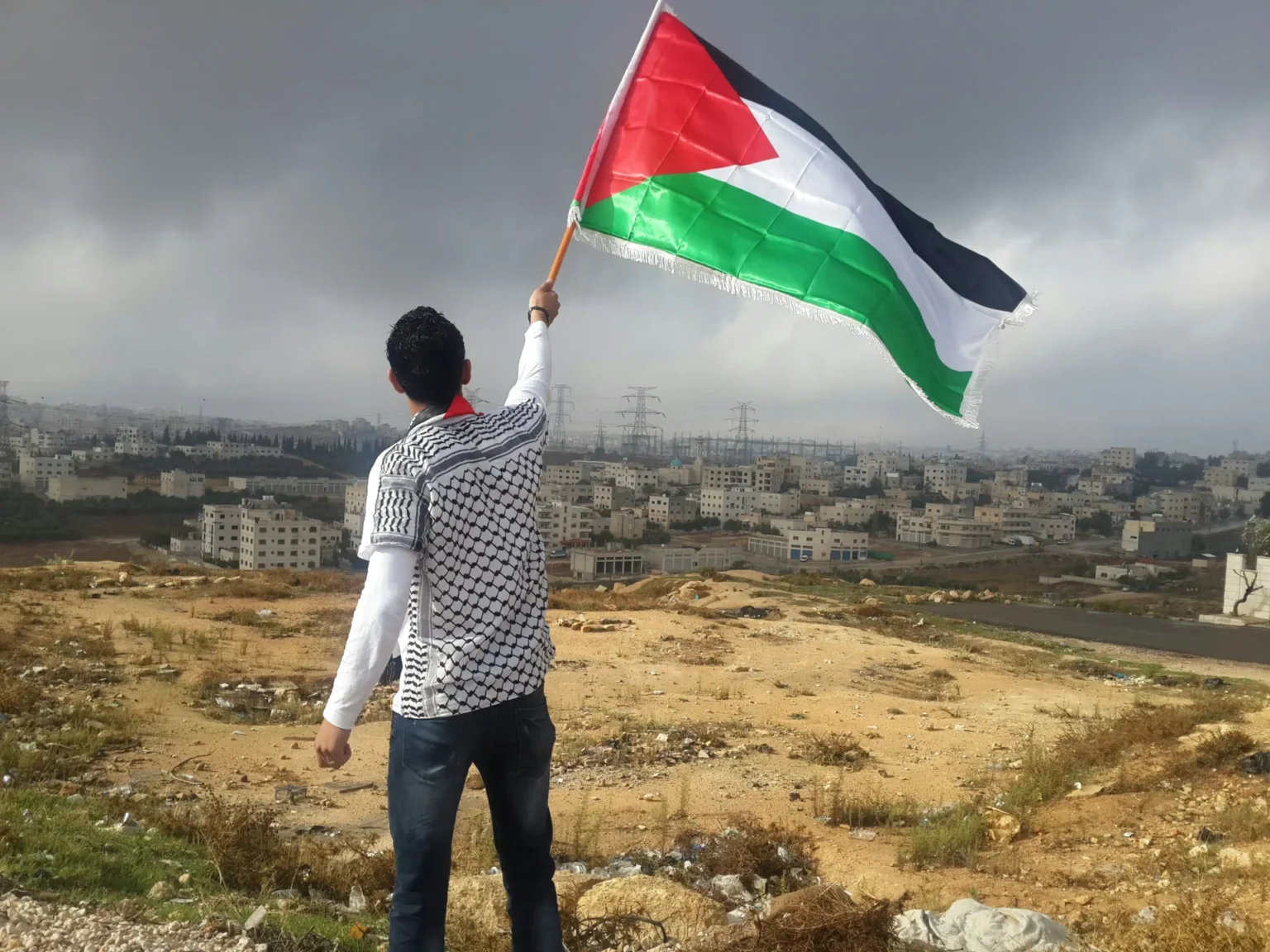 Relocation Plan For Gaza Triggers Uproar And Legal Alarm A man holding a Palestinian flag.