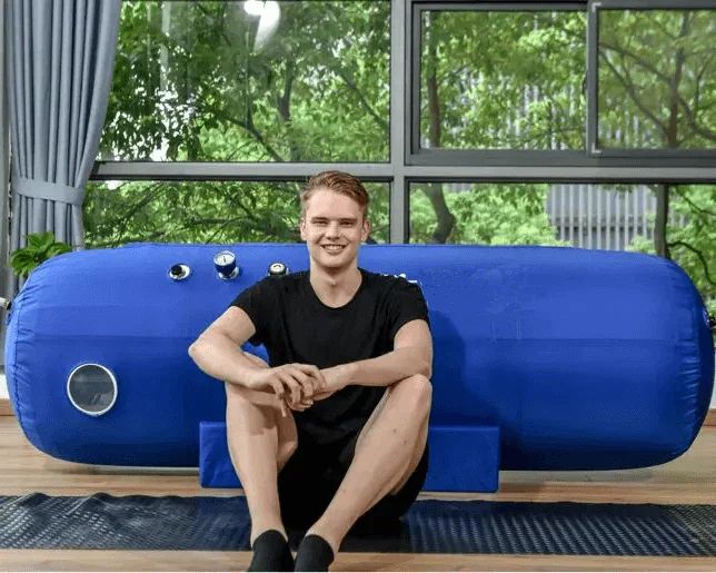 Hyperbaric Chamber Muscle Recovery Benefits & Athletic Performance Impact A man sitting next to hyperbaric chamber