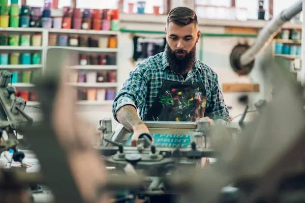 Beyond the Ink: How Emerging Technologies are Shaping Custom T-Shirt Printing a man using printing machine