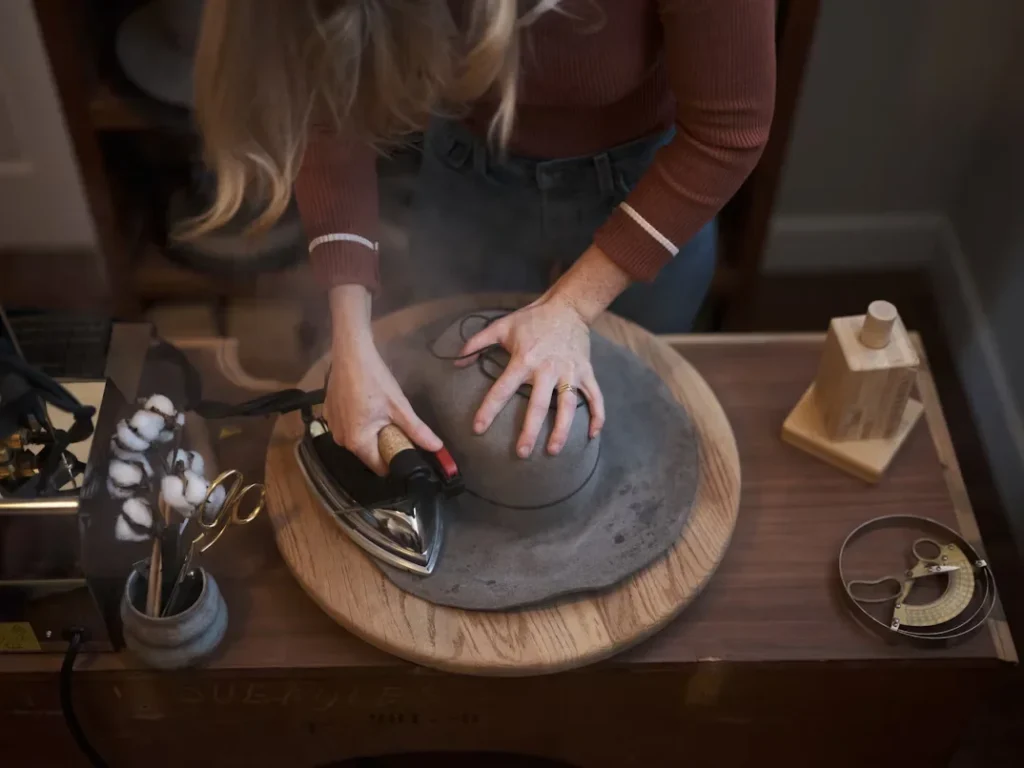 How to Source from Hat Manufacturers in China woman shapes a hat with iron