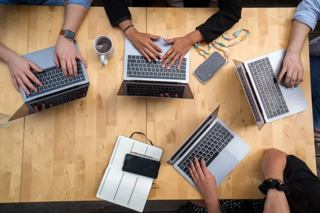 a group of people using laptop on wooden table