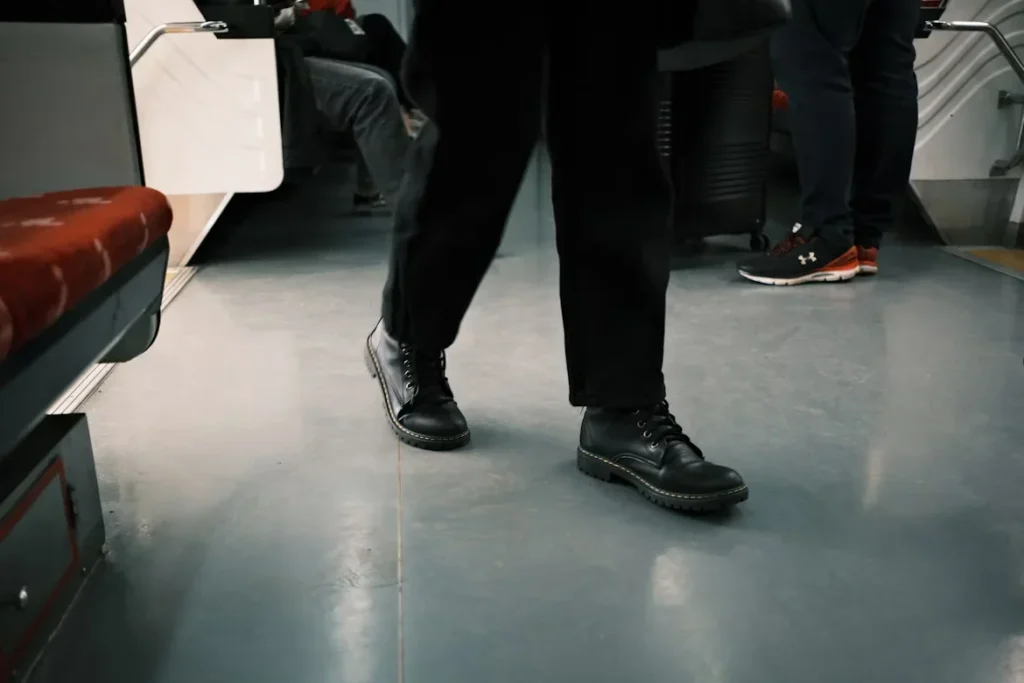 Non-Slip vs Slip-Resistant Shoes: Why the Difference Matters a person in black shoes standing on a train