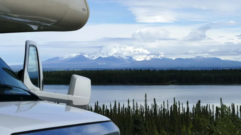 a truck parked next to a lake with mountains
