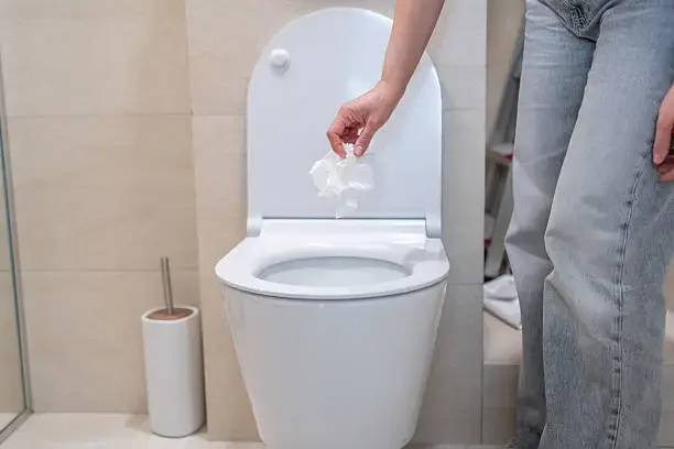 person throwing paper in the toilet