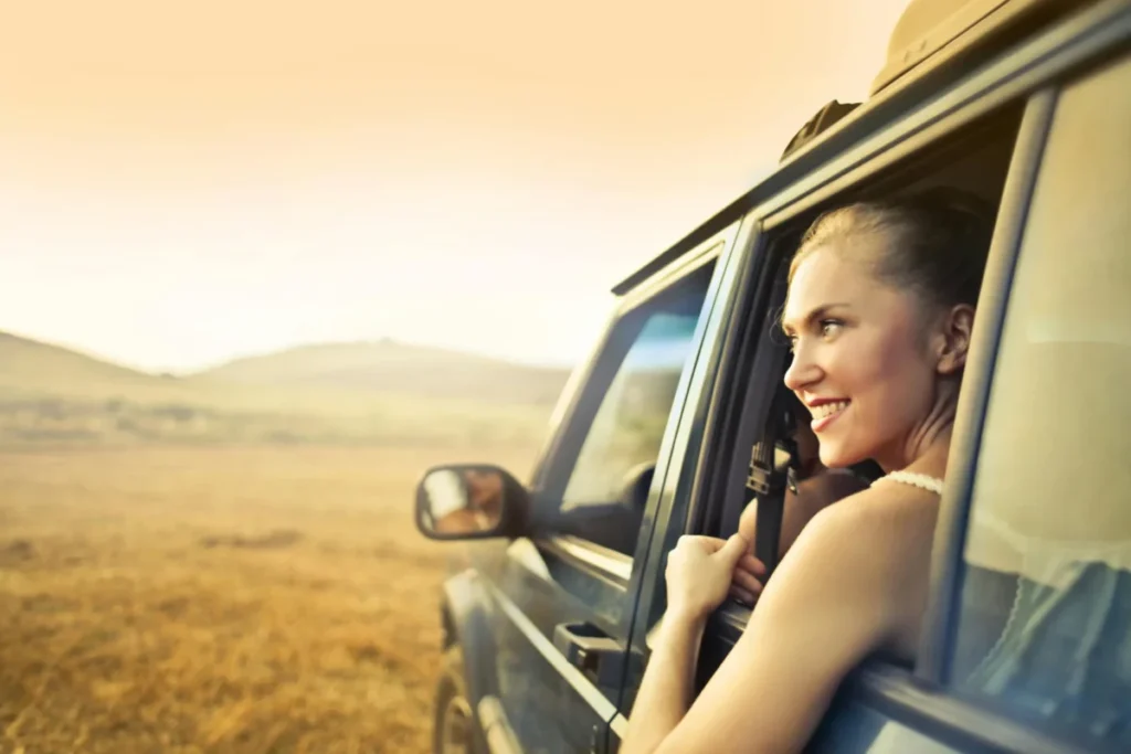 a woman sitting in car looking outside of teh window
