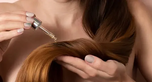 Beyond The Basics: How To Use Dry Shampoo To Extend Your Hair Care Routine a person applying oil in her hairs