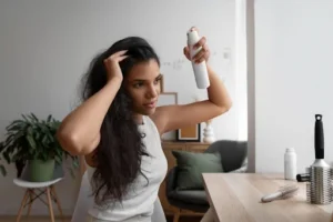 Beyond The Basics: How To Use Dry Shampoo To Extend Your Hair Care Routine woman applying dry shampoo in her hair